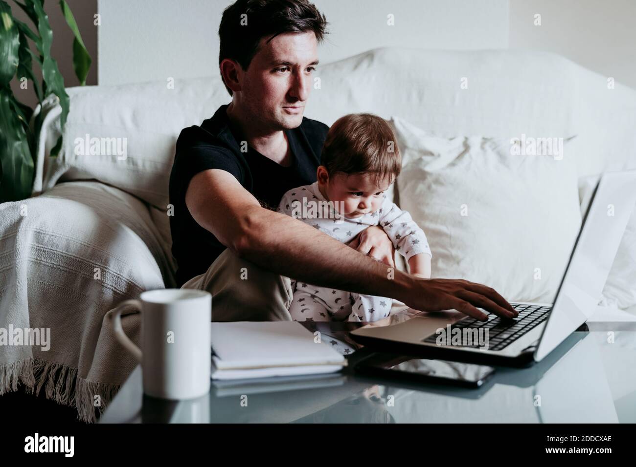 Father using laptop while son sitting on his lap at home Stock Photo ...