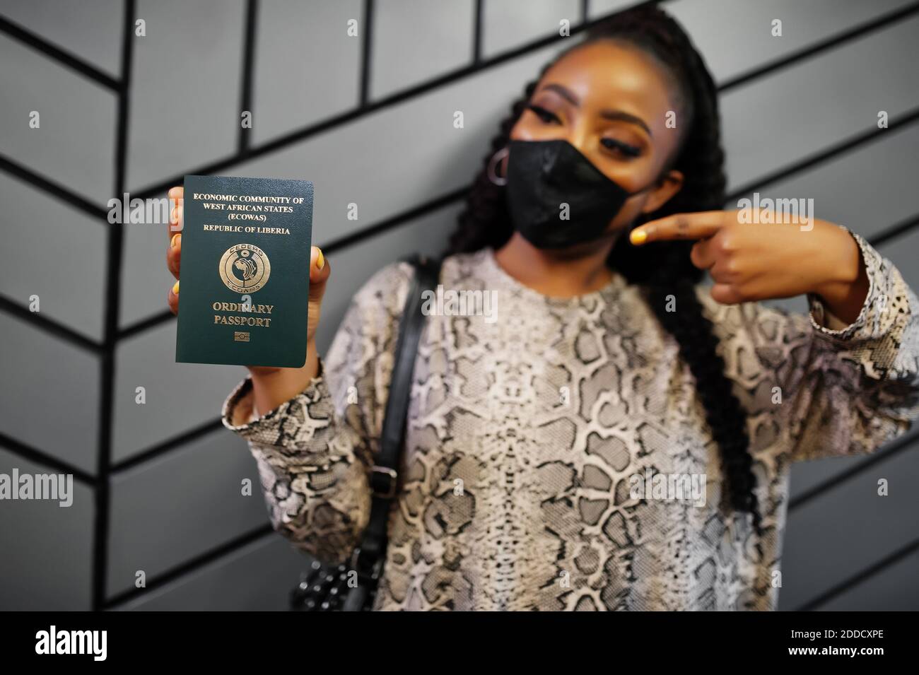 African woman wearing black face mask show Liberia passport in hand. Coronavirus in Africa country, border closure and quarantine, virus outbreak conc Stock Photo