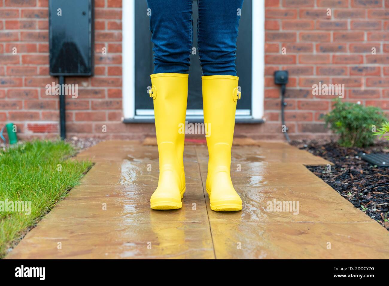 Woman wearing rubber boot standing in back yard during rainy season Stock Photo