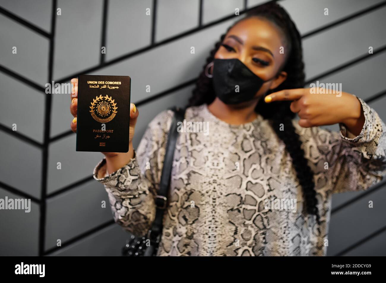 African woman wearing black face mask show Comoros passport in hand. Coronavirus in Africa
