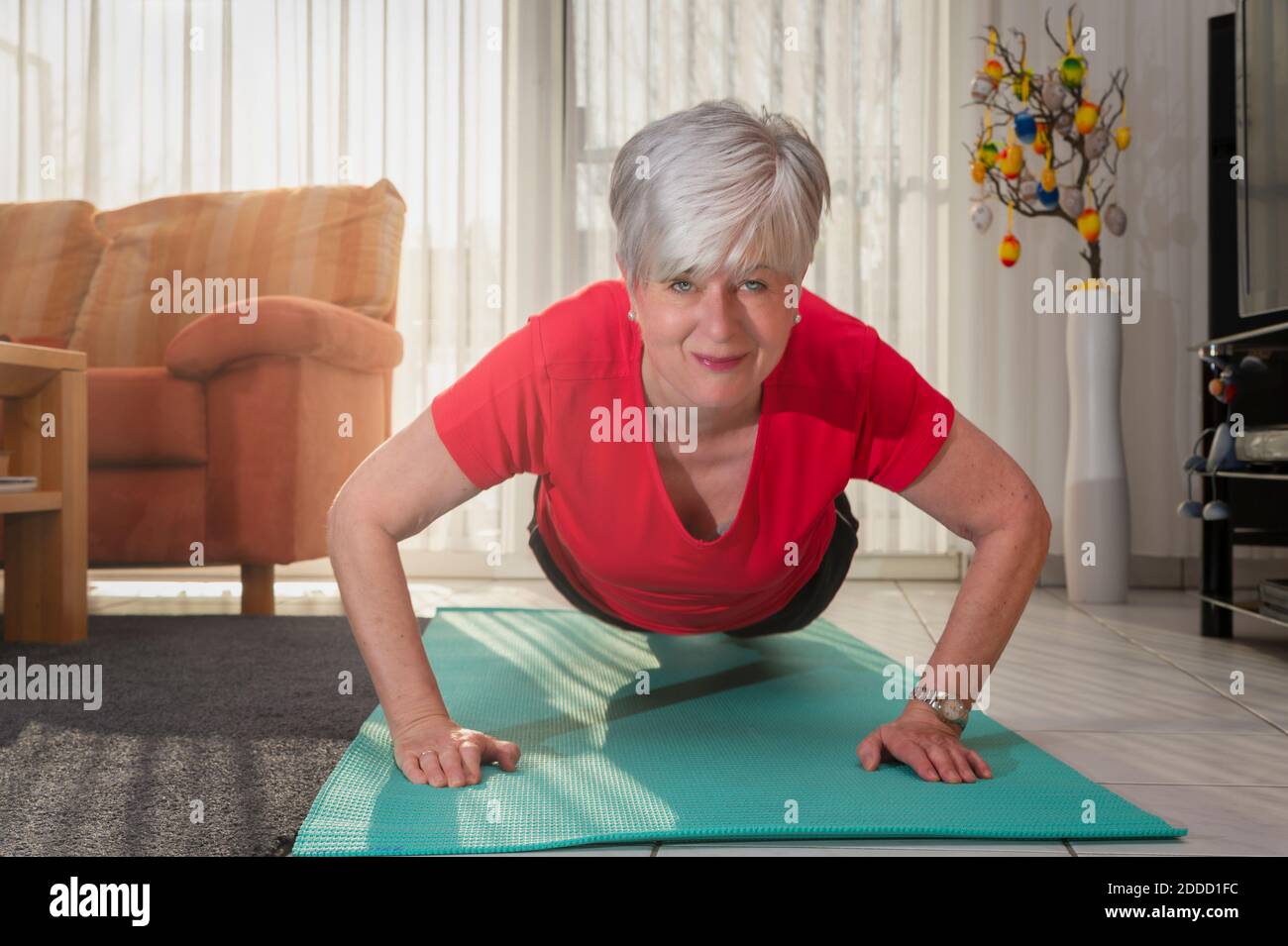 Happy senior woman doing pushup at home Stock Photo