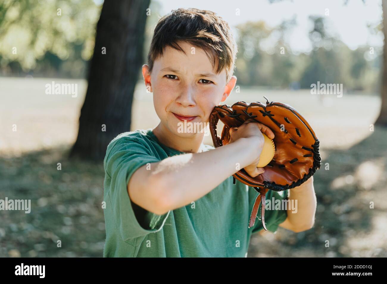 Boy wearing baseball glove while standing in public park Stock Photo