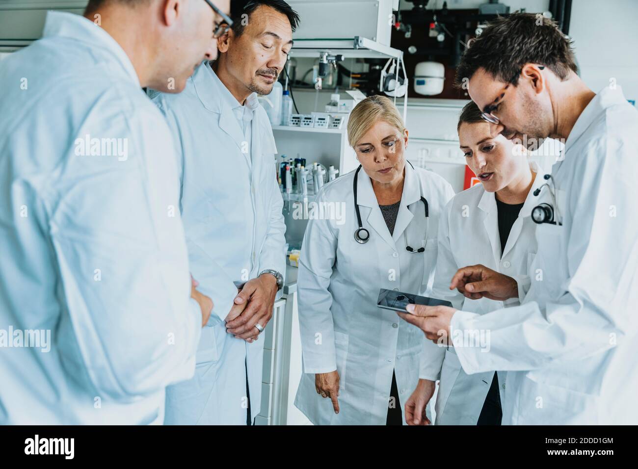 Scientist team working together on digital tablet while standing at laboratory Stock Photo