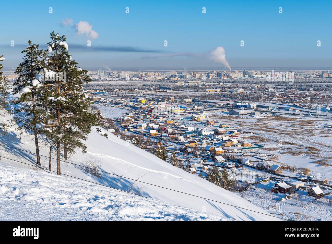 Russia, Republic of Sakha, Yakutsk, Snowcapped hill with city houses in background Stock Photo