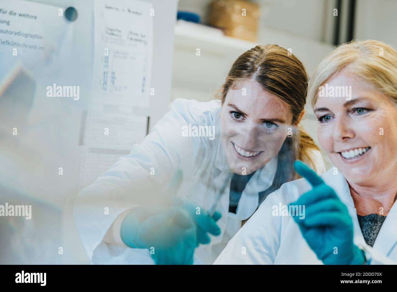 Smiling scientist and assistant discussing while examining human brain microscope slide at