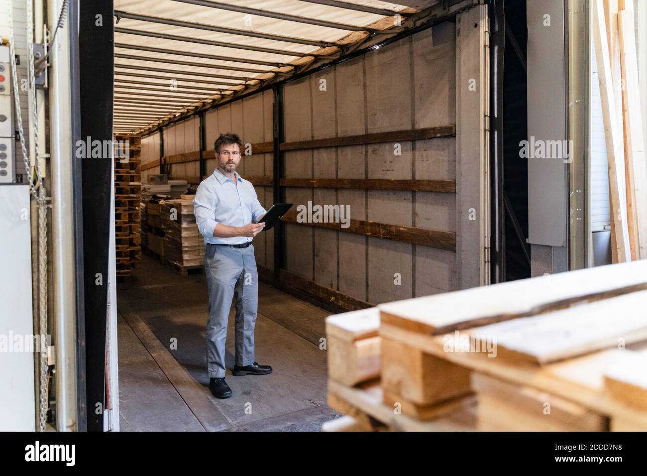 Inspector with digital tablet loading material while standing in delivery truck Stock Photo