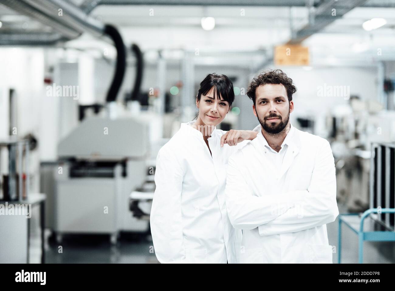 Male and female scientists in white lab coats standing at bright