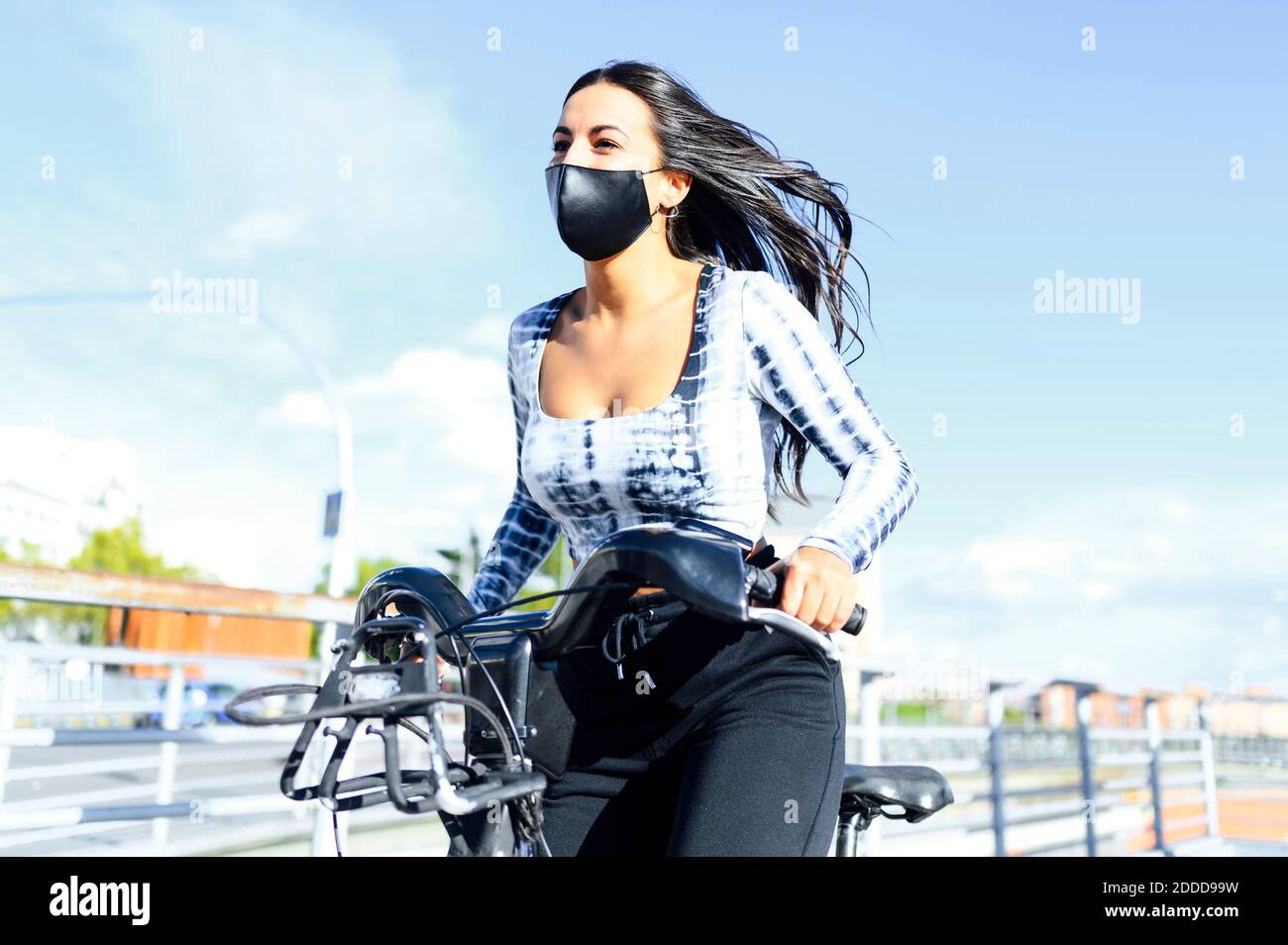 Woman wearing protective face mask cycling on bicycle during sunny day Stock Photo