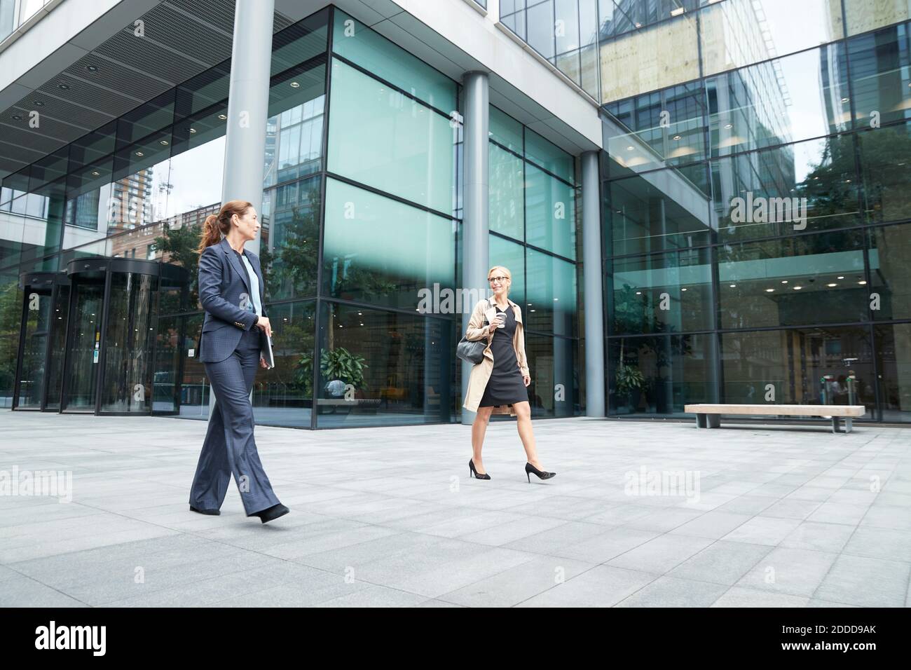 Colleague talking while walking against office building exterior Stock Photo