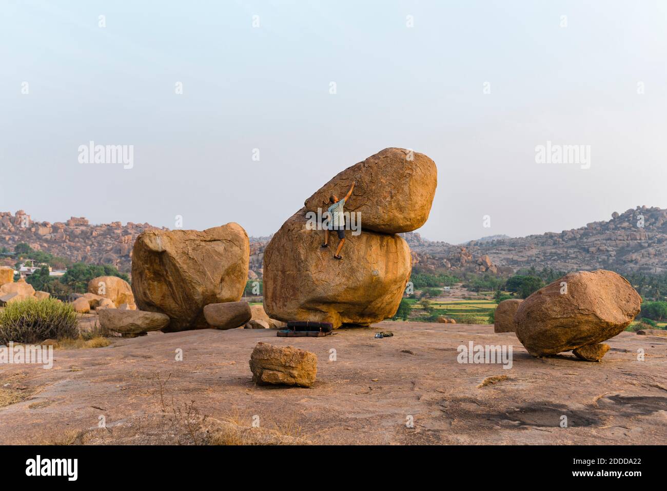 Mature man climbing boulder rock, Karnataka, Hampi, India Stock Photo