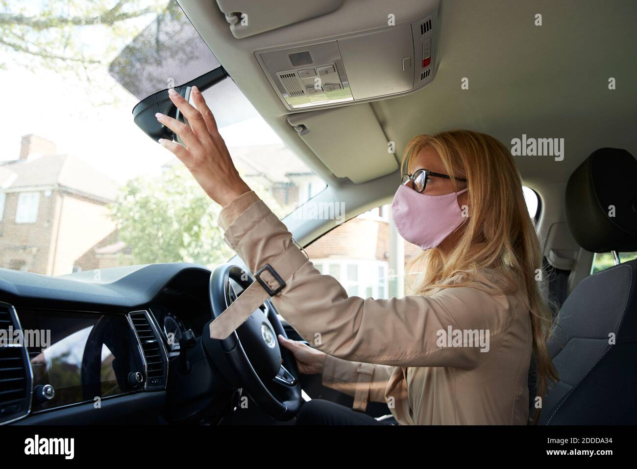 Mature woman adjusting rear view mirror while sitting in car Stock Photo