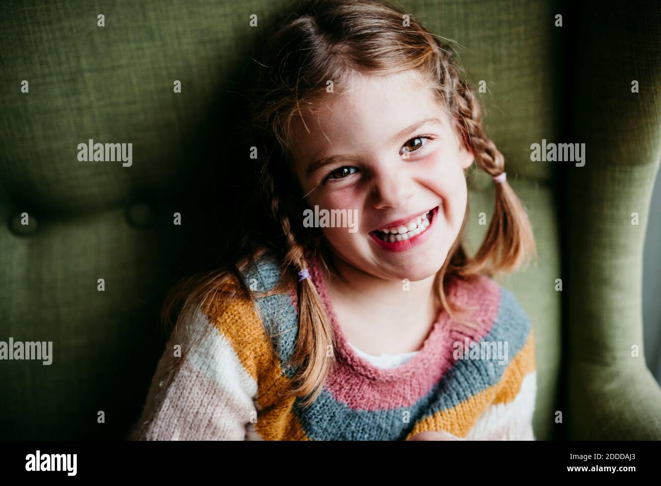 Smiling girl sitting on sofa at home Stock Photo - Alamy