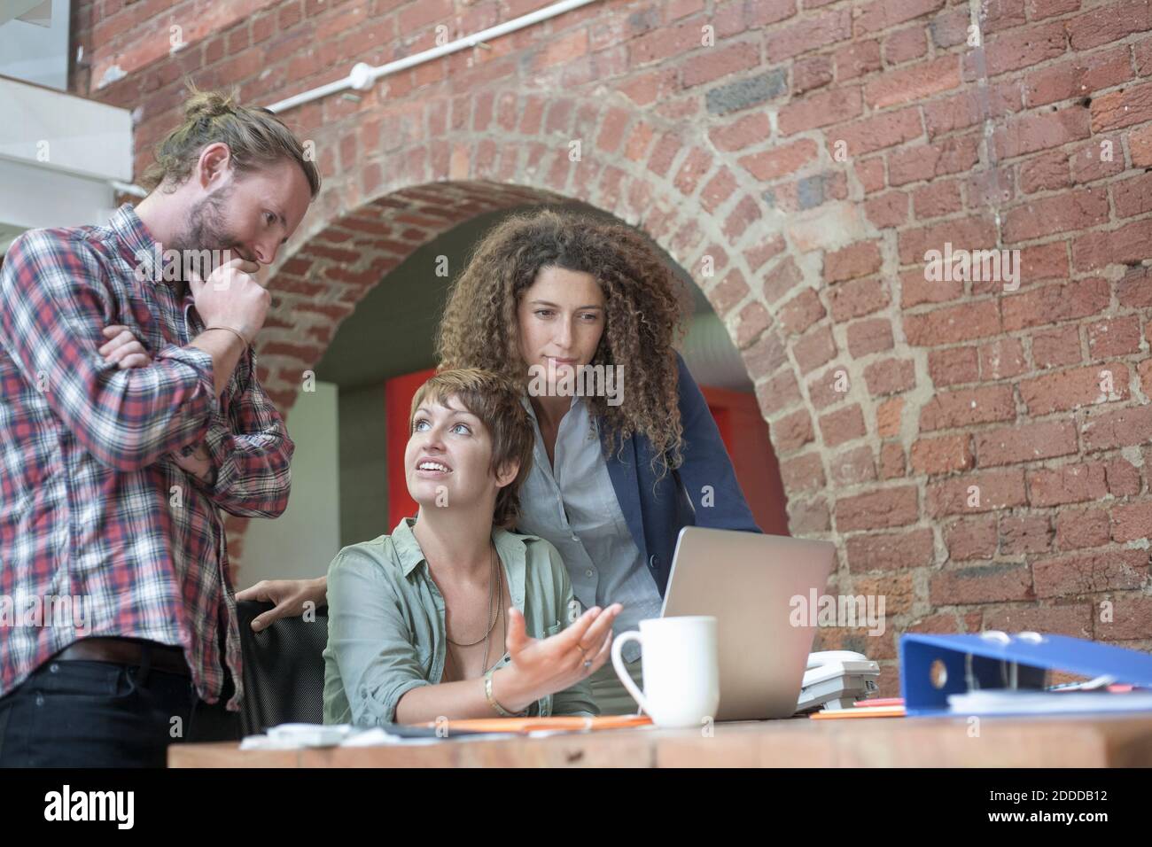 Employees discussing while working together at office Stock Photo