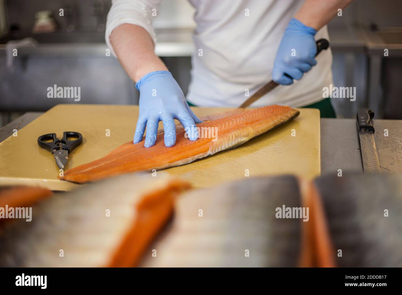 Man cutting fish at counter in food processing plant Stock Photo
