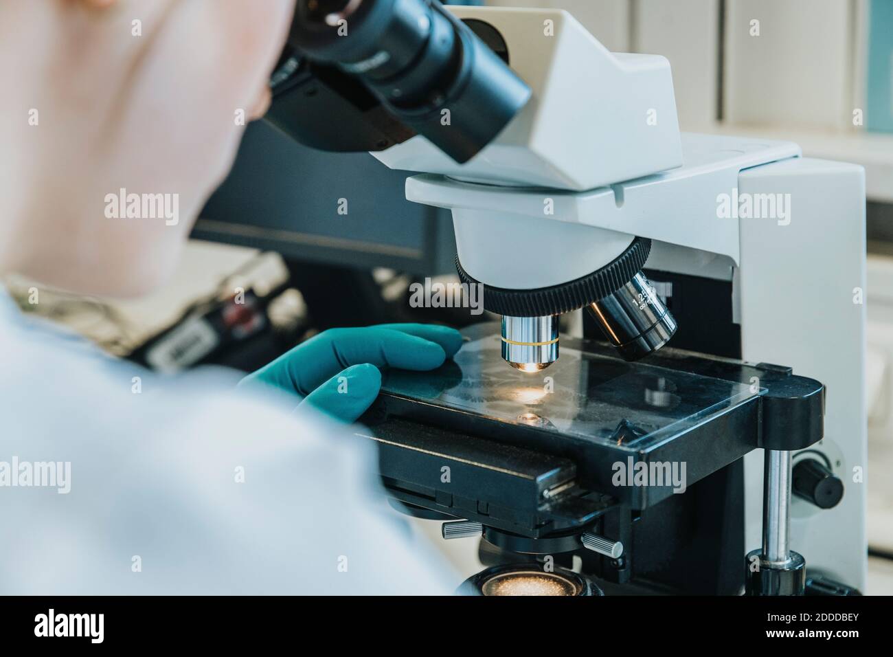 Young woman analyzing human brain microscope slide under microscope