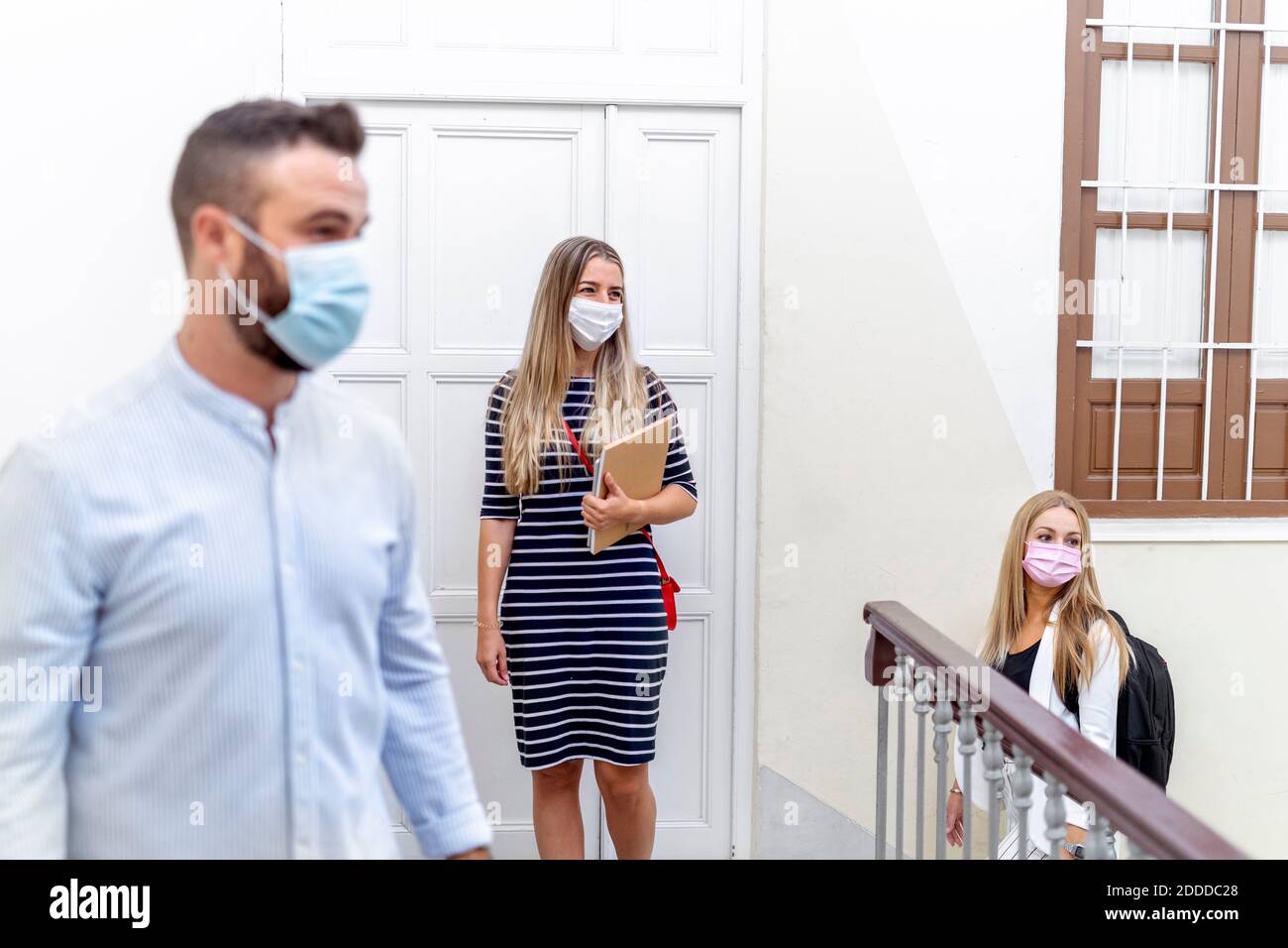 Coworkers maintaining social distance while entering at office Stock Photo
