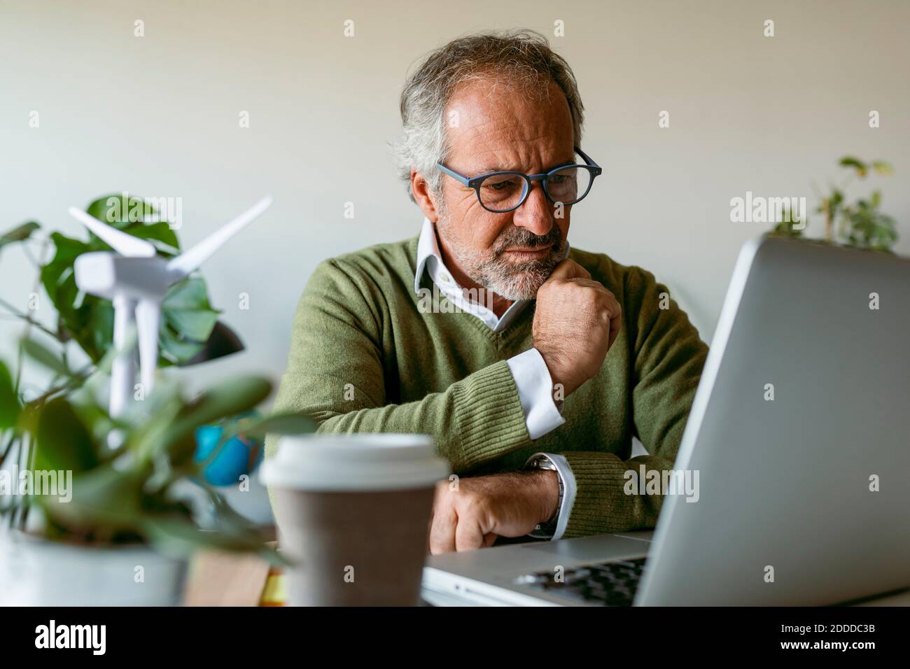 Man wearing eyeglasses using laptop while sitting by table at home Stock Photo