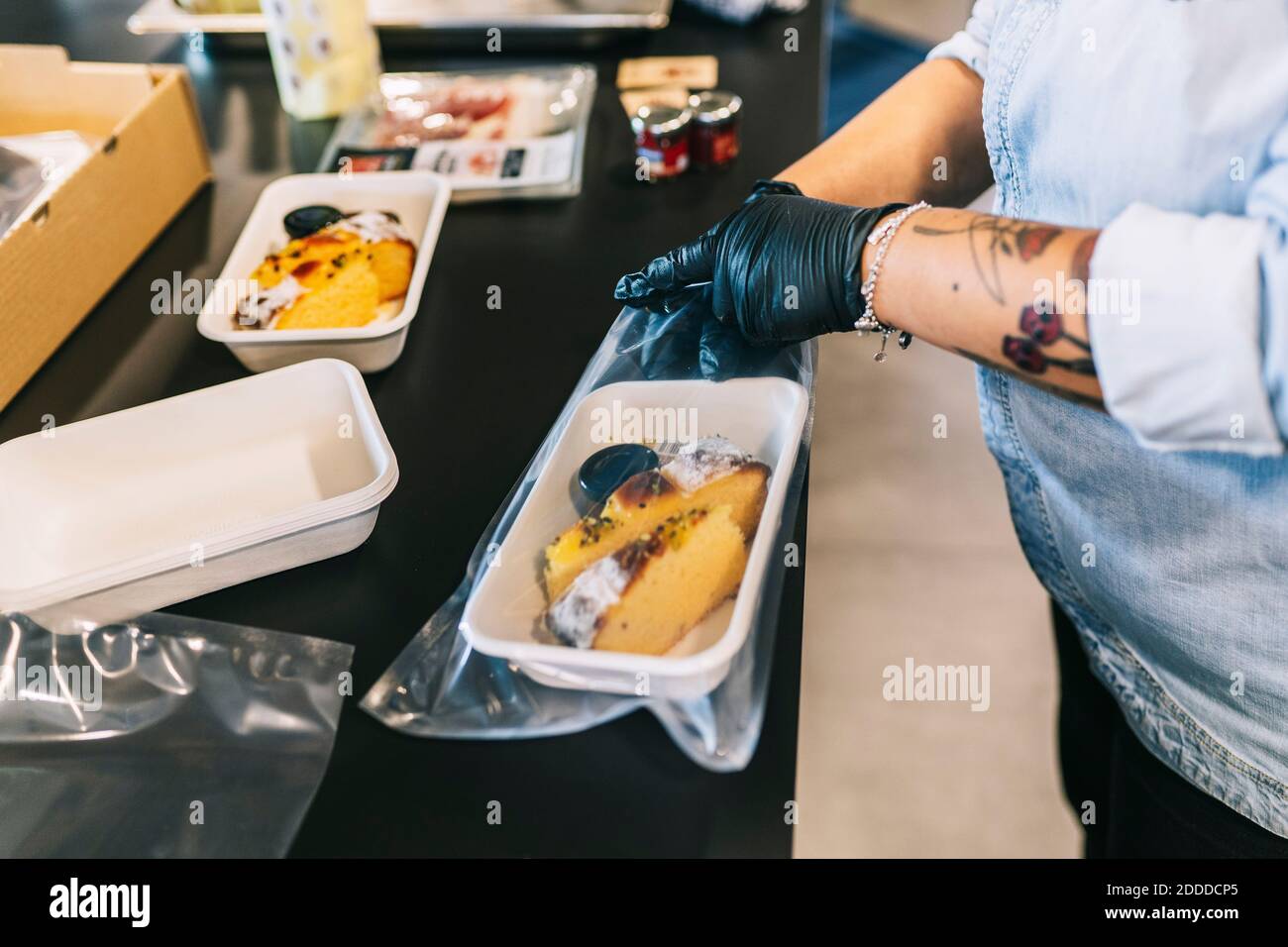 Midsection of female chef putting fresh take out meal in plastic bag at restaurant Stock Photo