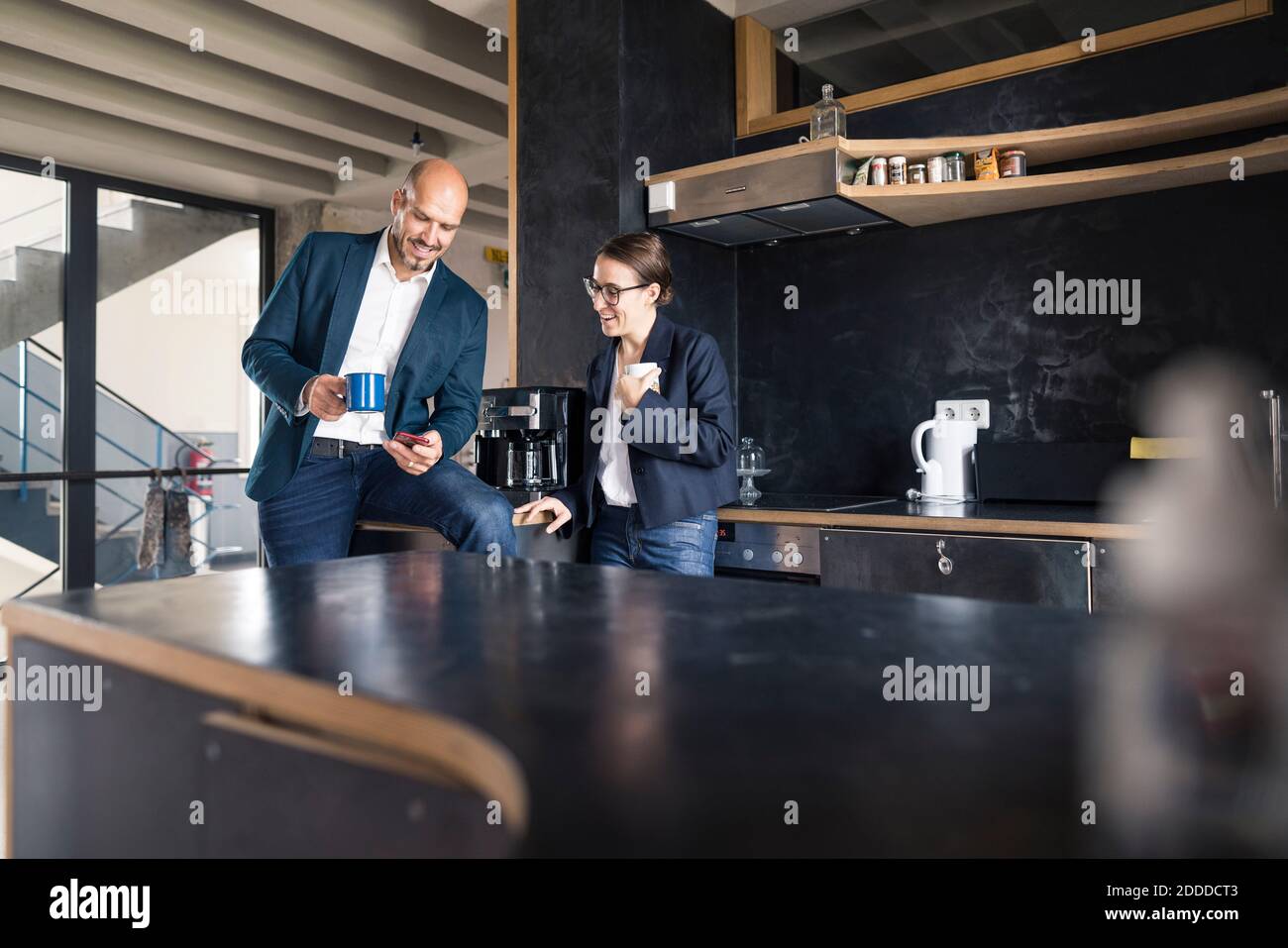 Business people using mobile phone while drinking coffee at office Stock Photo
