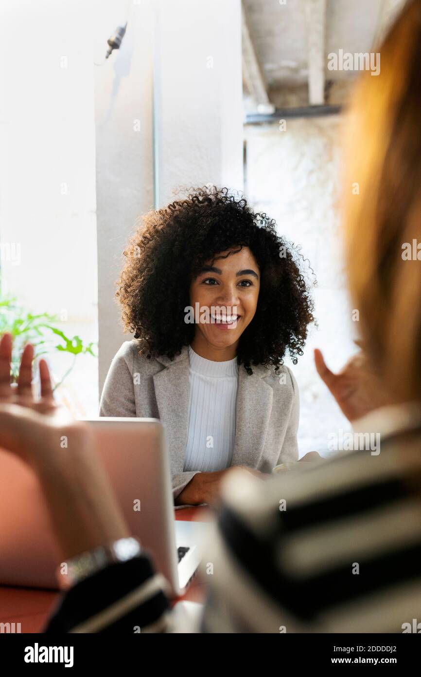 Smiling coworkers discussing while sitting in cafe Stock Photo