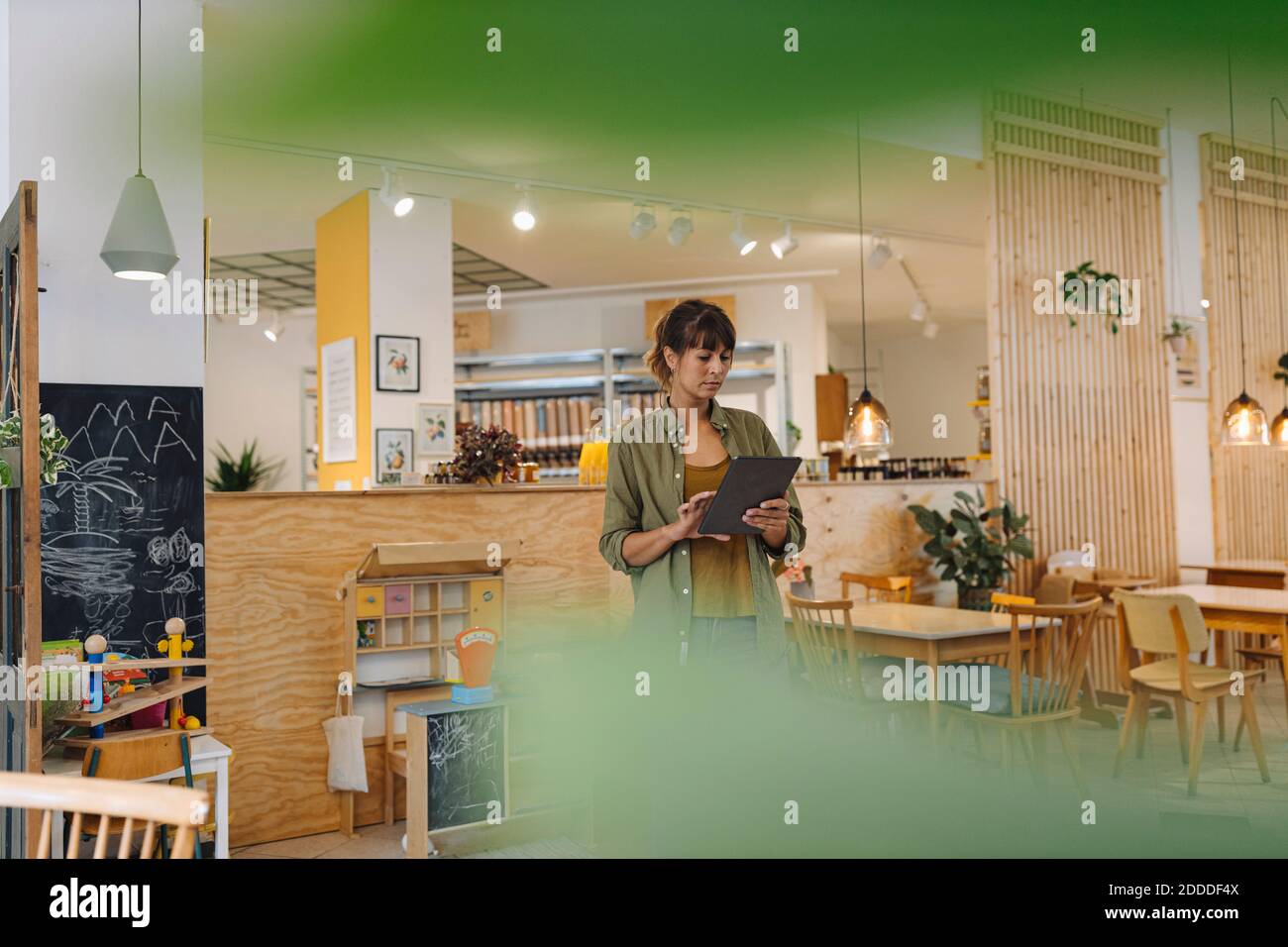 Female owner using digital tablet while standing in coffee shop Stock Photo
