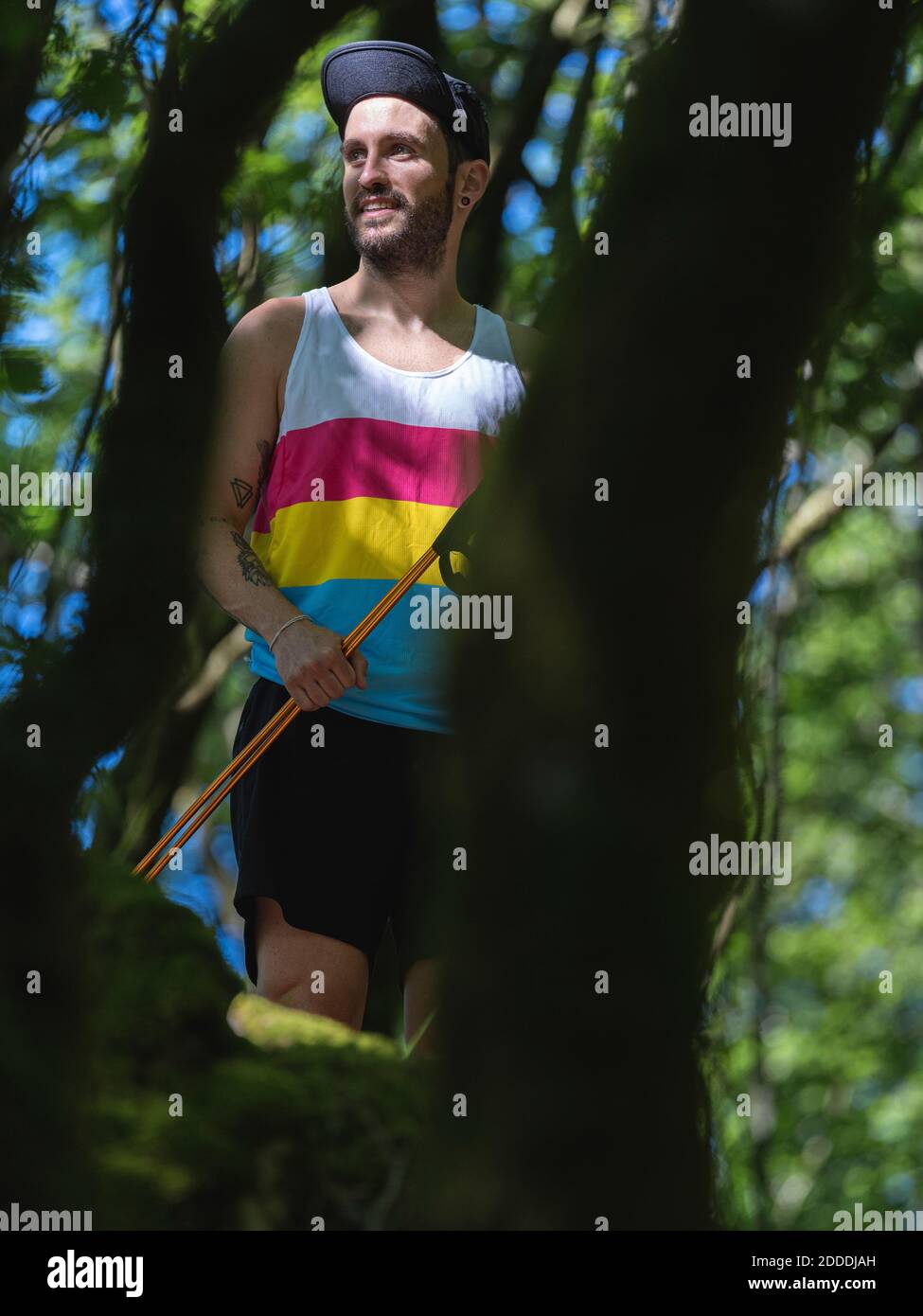 Athlete holding hiking pole while standing at forest Stock Photo