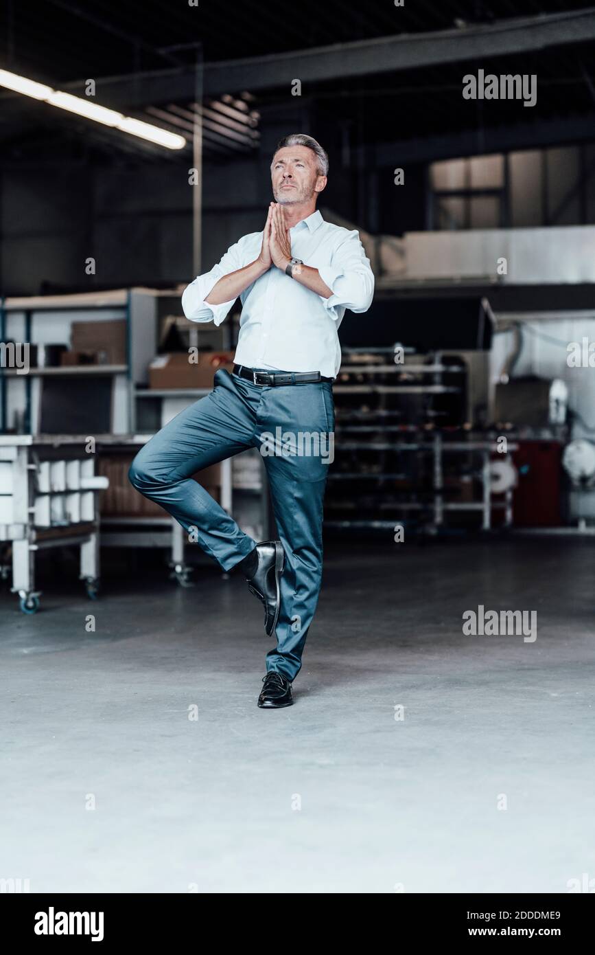 Male engineer with hands clasped standing on one leg in manufacturing industry Stock Photo