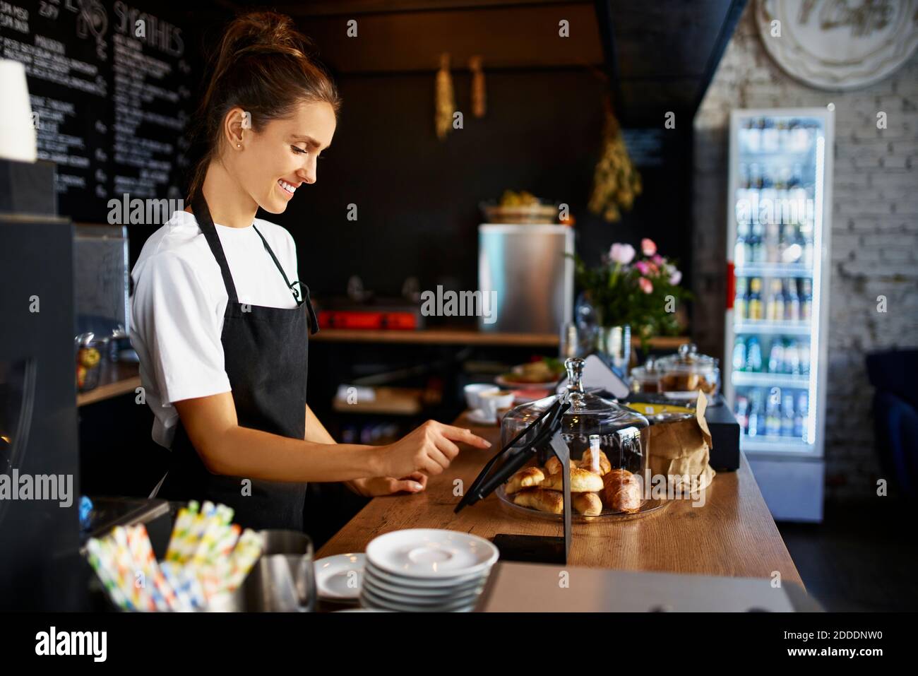 Smiling barista using digital tablet at kitchen counter in cafe Stock Photo