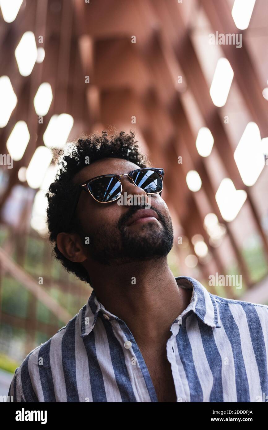 Contemplating man wearing sunglasses while standing in city Stock Photo -  Alamy