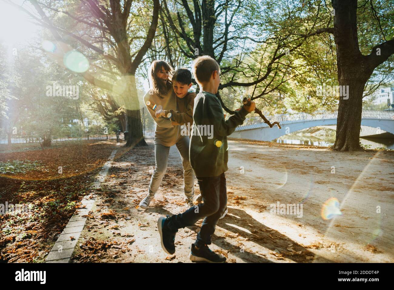 Mother embracing sons while walking in public park Stock Photo