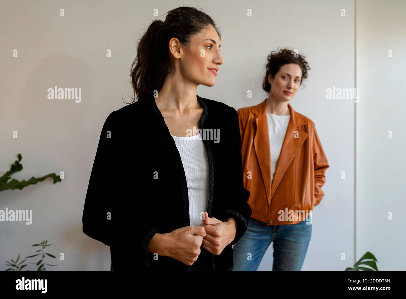 Female models wearing jacket standing against wall at home Stock Photo