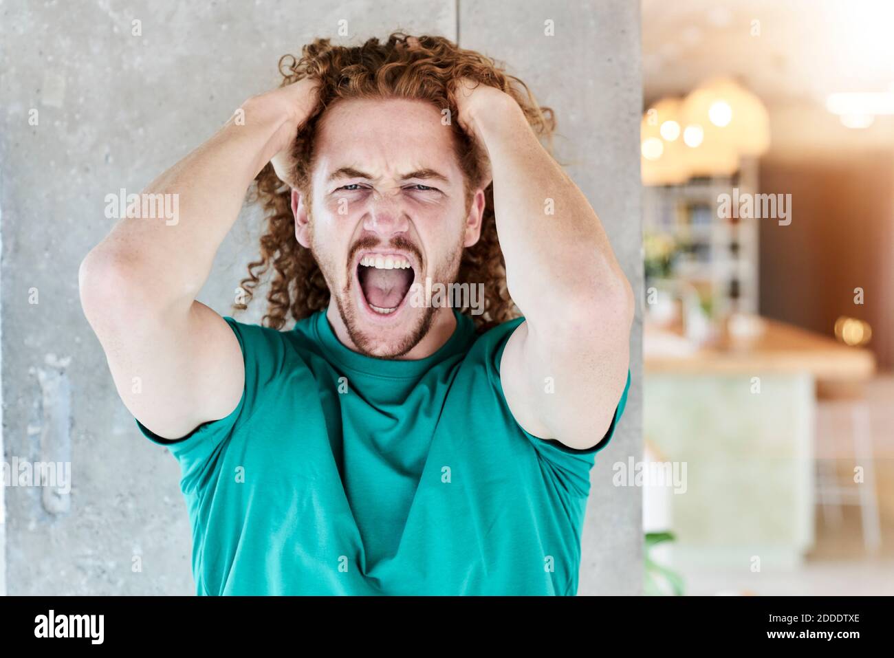 Man in aggression shouting while standing against column at home Stock Photo