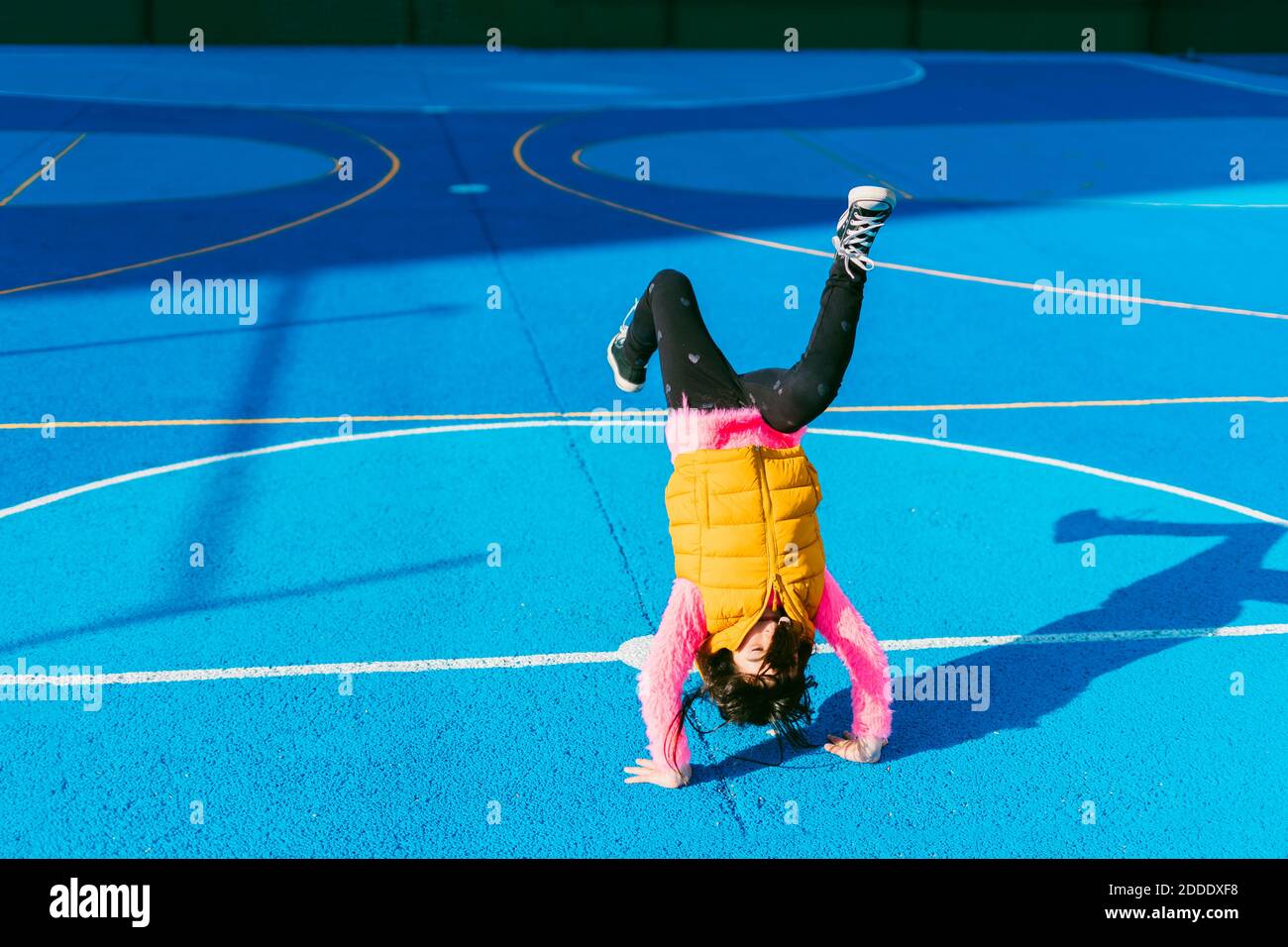 Playful girl practicing handstand on soccer court Stock Photo
