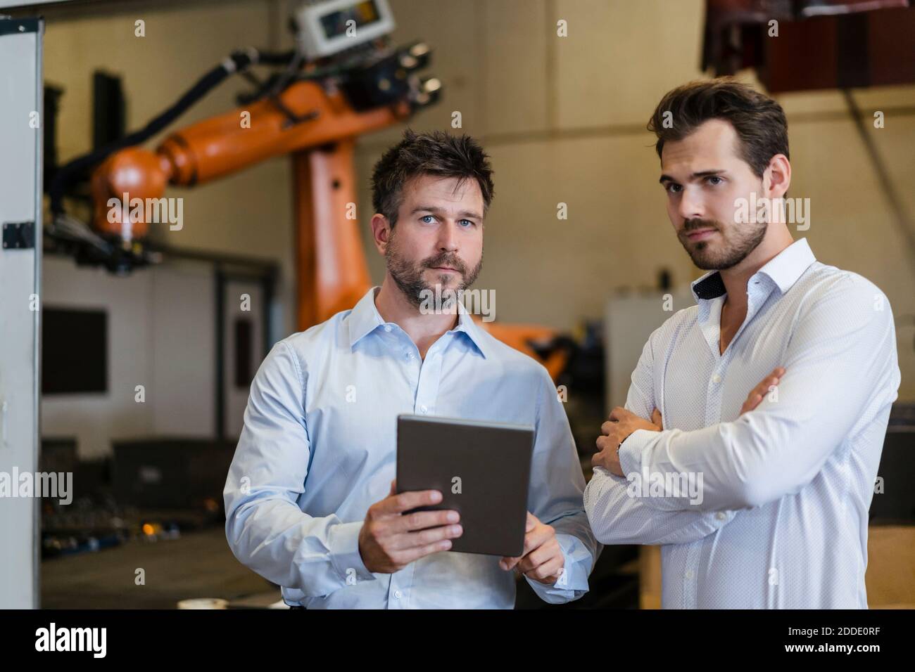 Confident businessmen using digital tablet while standing at factory Stock Photo