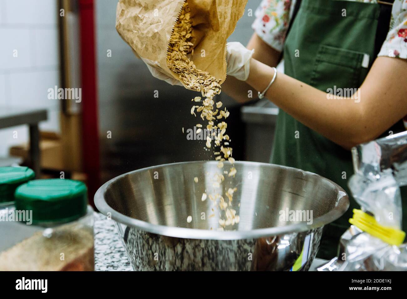 Female baker pouring ingredient in mixing bowl at bakery kitchen Stock