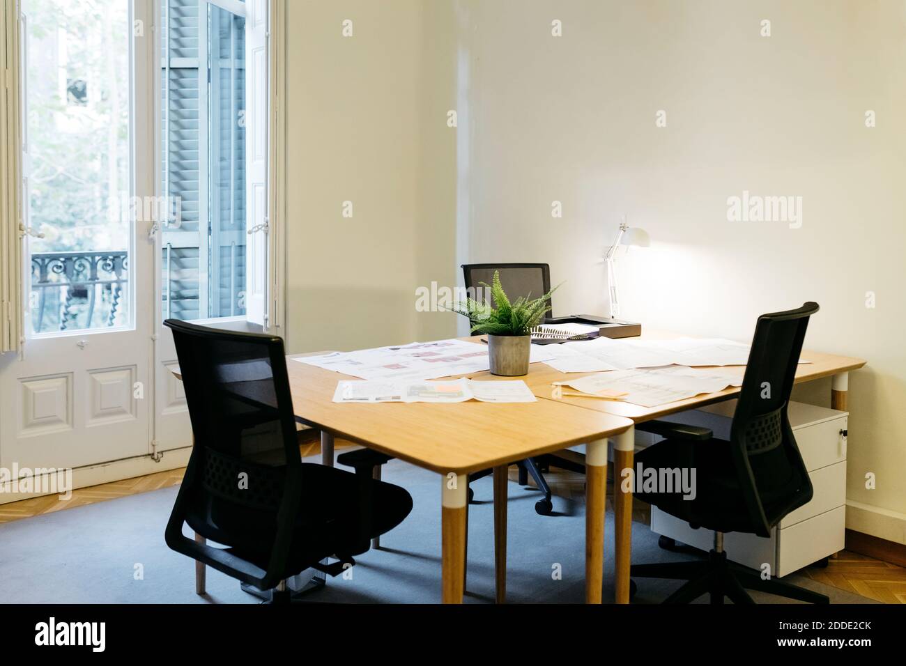 Empty chair arranged with papers over table at workplace Stock Photo