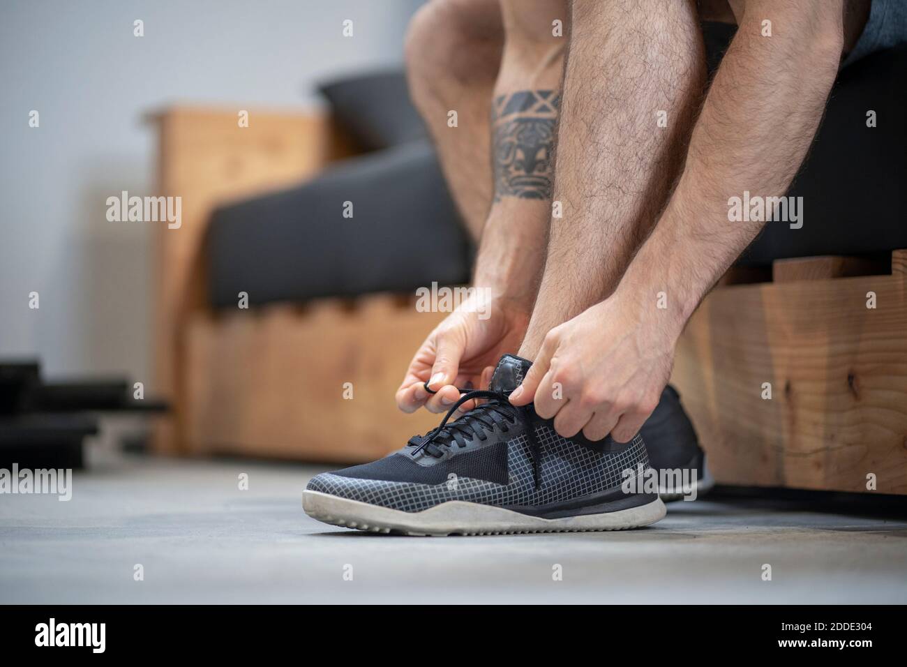 Close-up of man tying shoelace while sitting on bed at home Stock Photo