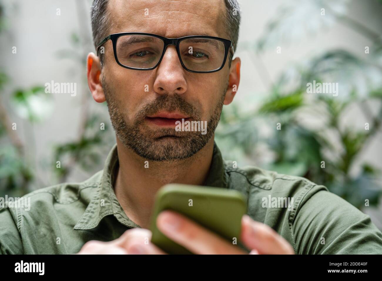 Businessman wearing eyeglasses using mobile phone at cafe Stock Photo Alamy