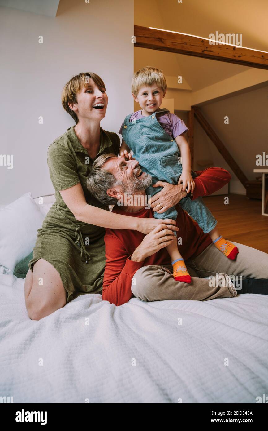 Mother and father embracing son while sitting on bed at home Stock Photo