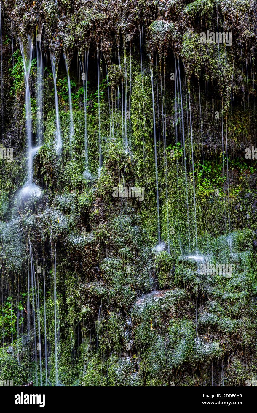 Streams of Burgbach Waterfall splashing down mossy rock wall Stock Photo