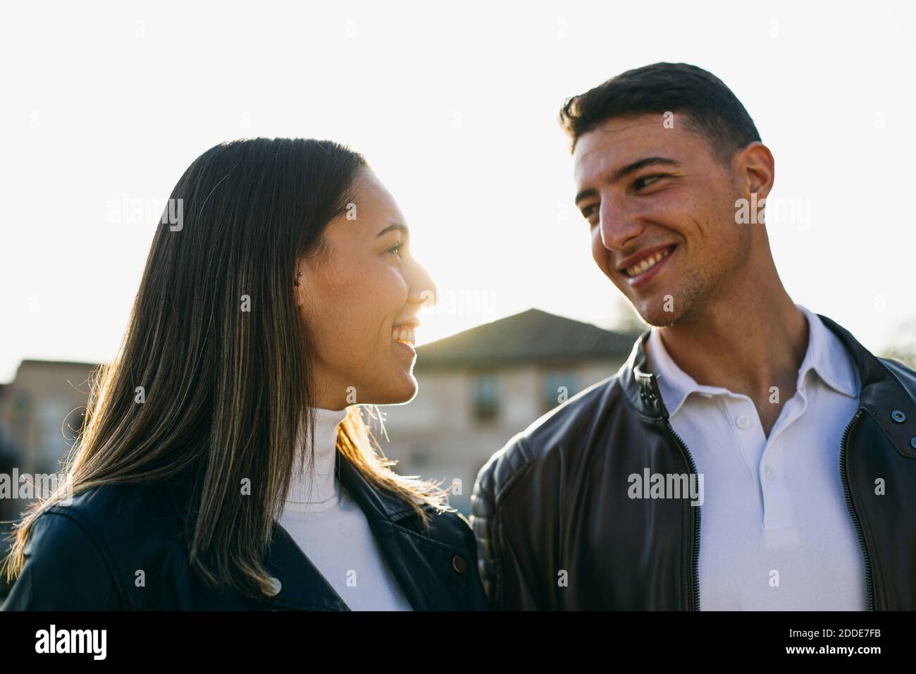 Couple smiling while looking at each other outdoors Stock Photo