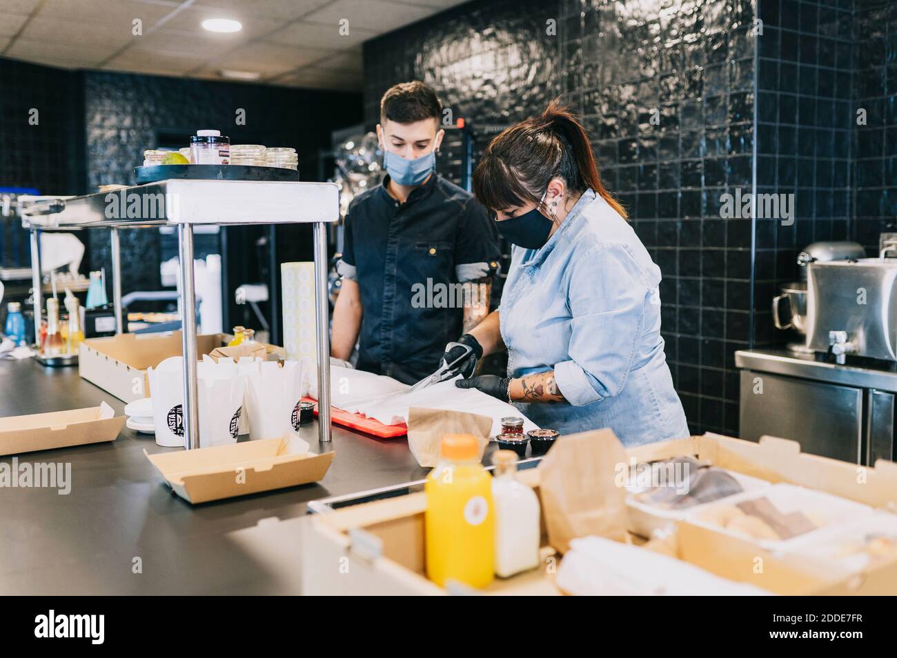 Male and female coworkers preparing take out meal at kitchen counter in restaurant Stock Photo