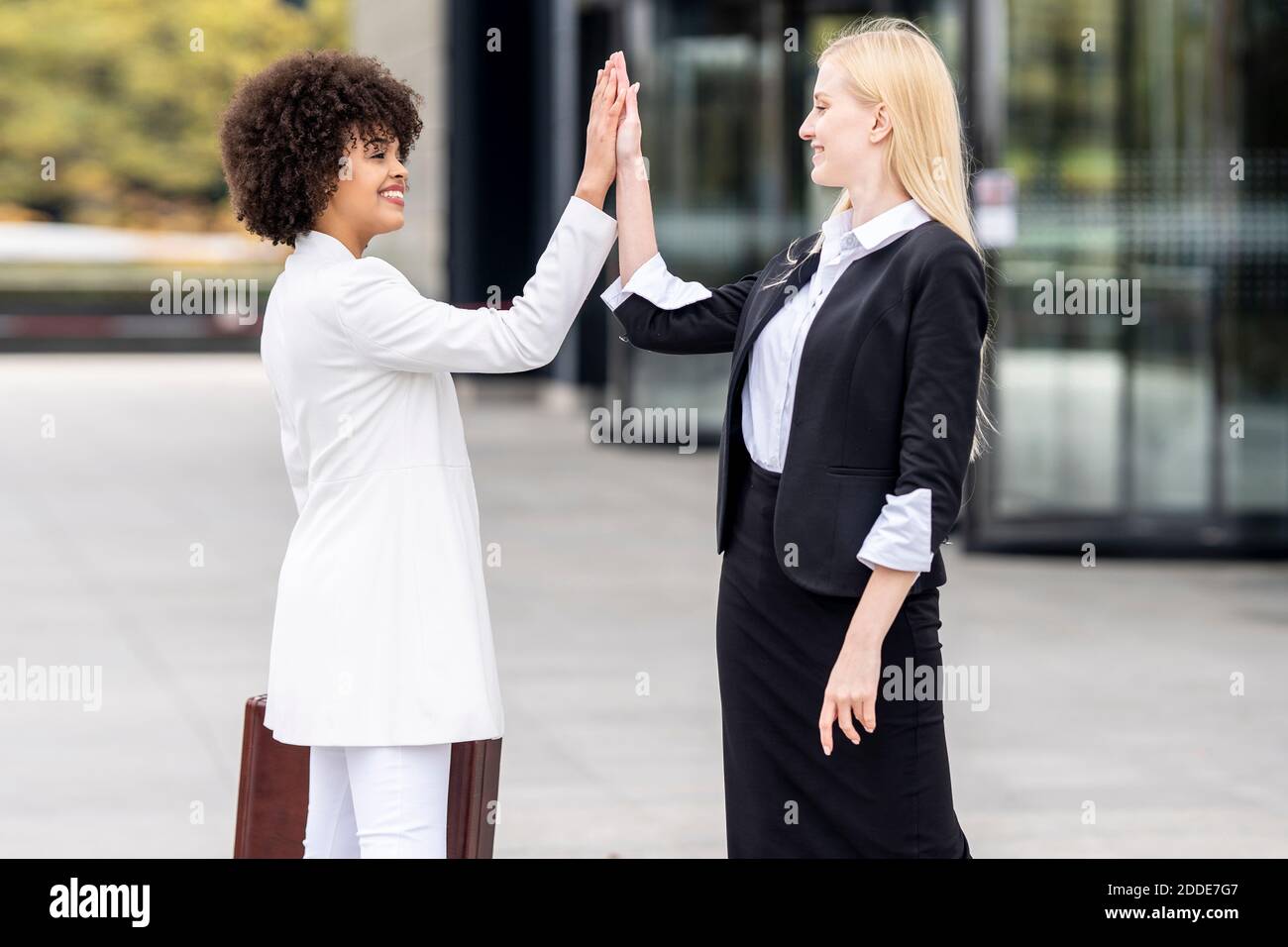 Business people greeting with giving high-five while standing outdoors Stock Photo
