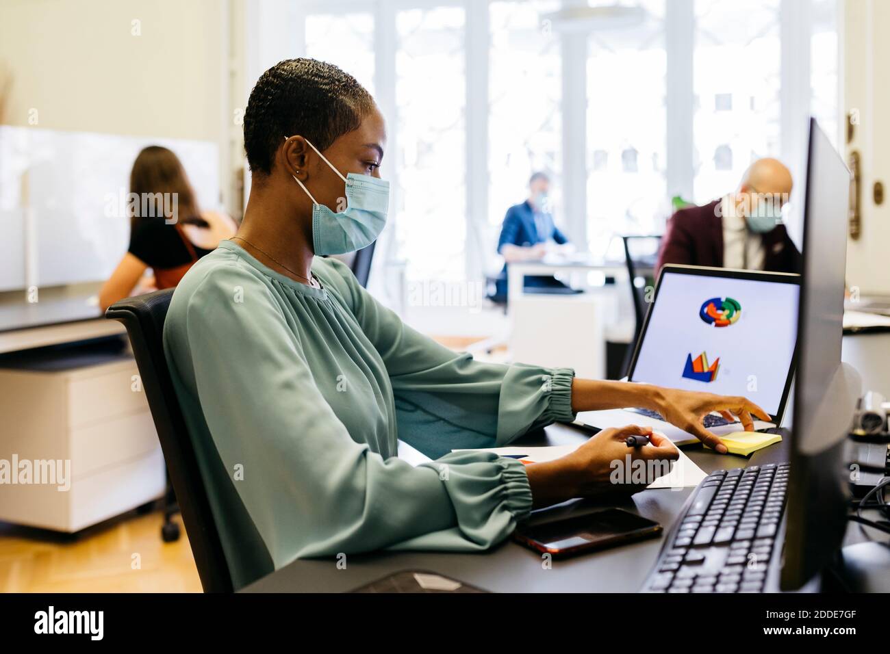 African businesswoman with safety mask working at office desk Stock ...
