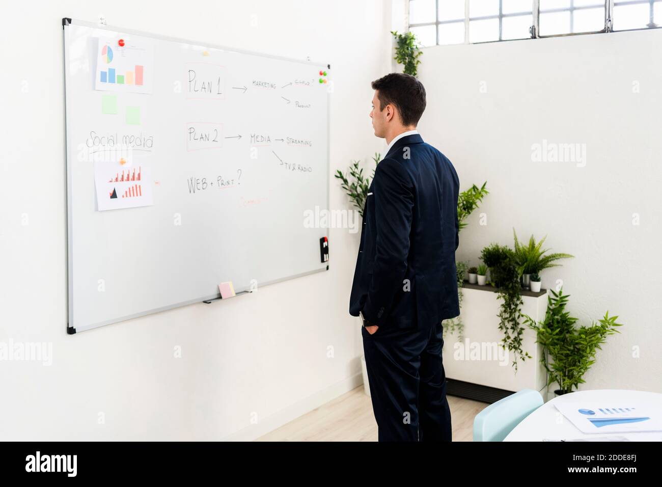 Young male entrepreneur looking at strategy on whiteboard in office Stock Photo