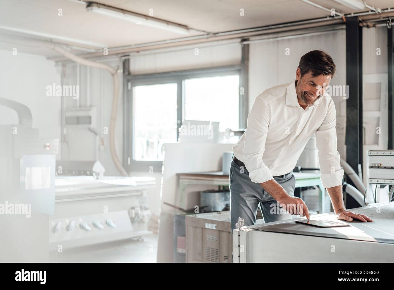 Smiling engineer using digital tablet in factory Stock Photo