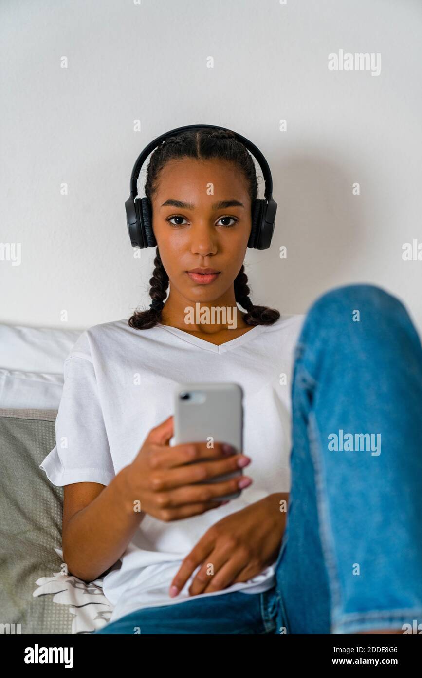 Young teenage girl listening to music through headphone on smart phone