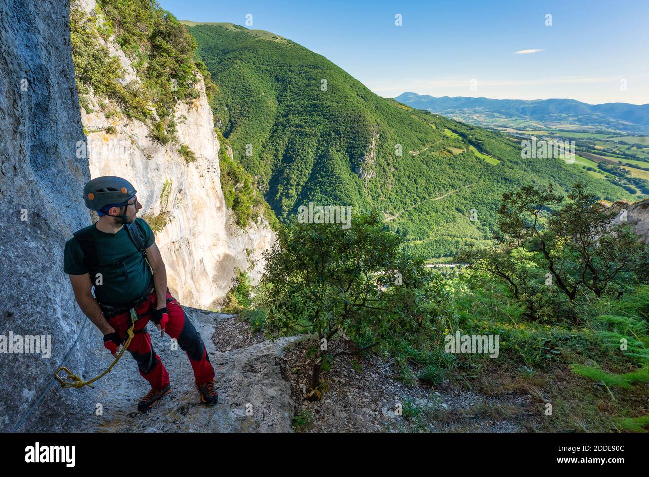 Male rock climber taking break to admire surrounding landscape of Apennine Mountains Stock Photo