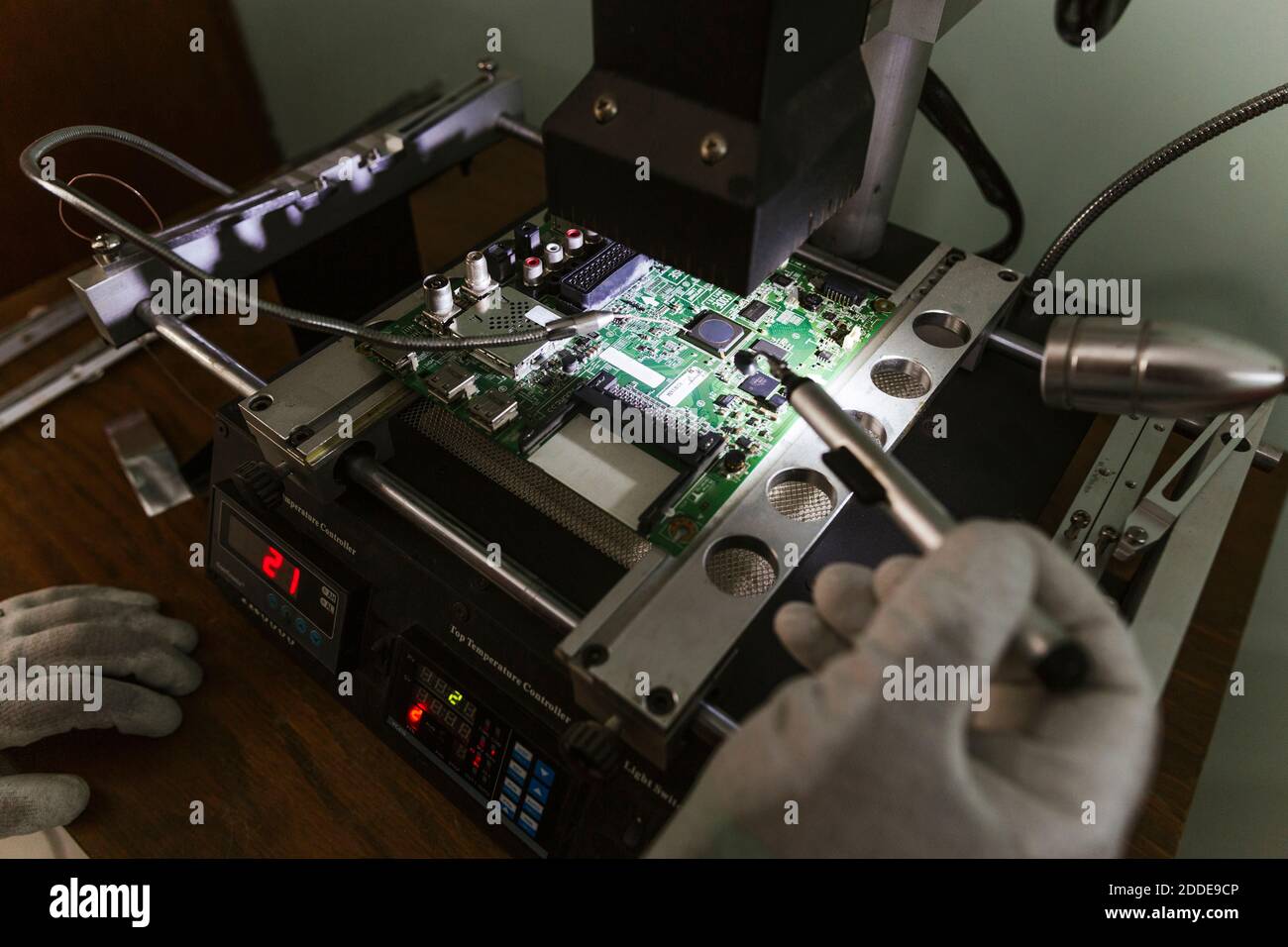 Electronics expert examining damaged circuit board at repair shop Stock Photo