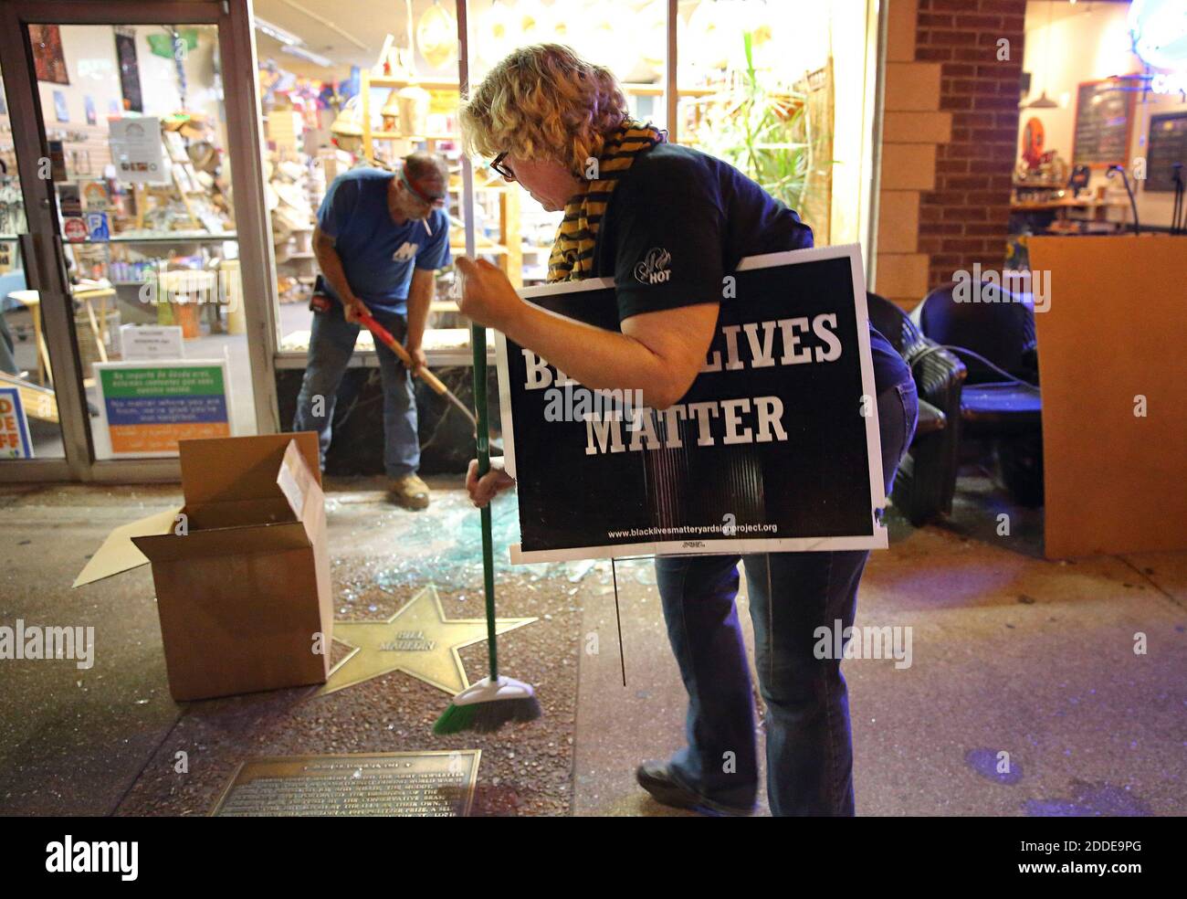 NO FILM, NO VIDEO, NO TV, NO DOCUMENTARY - University City resident Anne Worcester sweeps up broken glass after vandals shattered many windows as a line of police advanced east on Delmar Boulevard to end a protest in University City on Saturday, September 16, 2017. Earlier in the night a large peaceful protest blocked traffic and filled the streets with people. The earlier protest had no property damage and no arrests. But after many of those protesters had left a second more confrontational protest started along Delmar Boulevard. Some people in the crowd threw objects at the police, vandalize Stock Photo